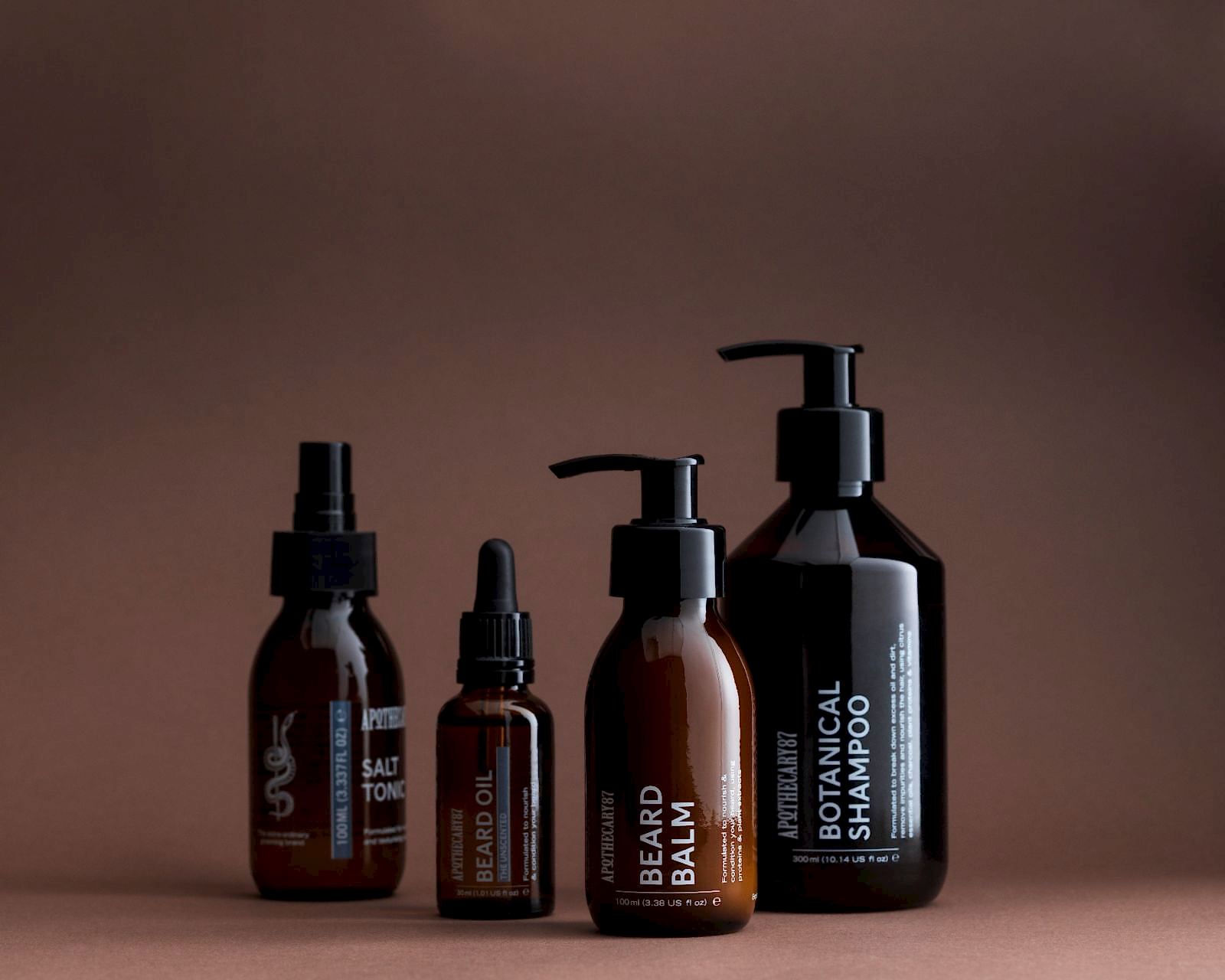 4 brown glass bottles of Apothecary 87 grooming products - branding and packaging design by 93ft Design. 