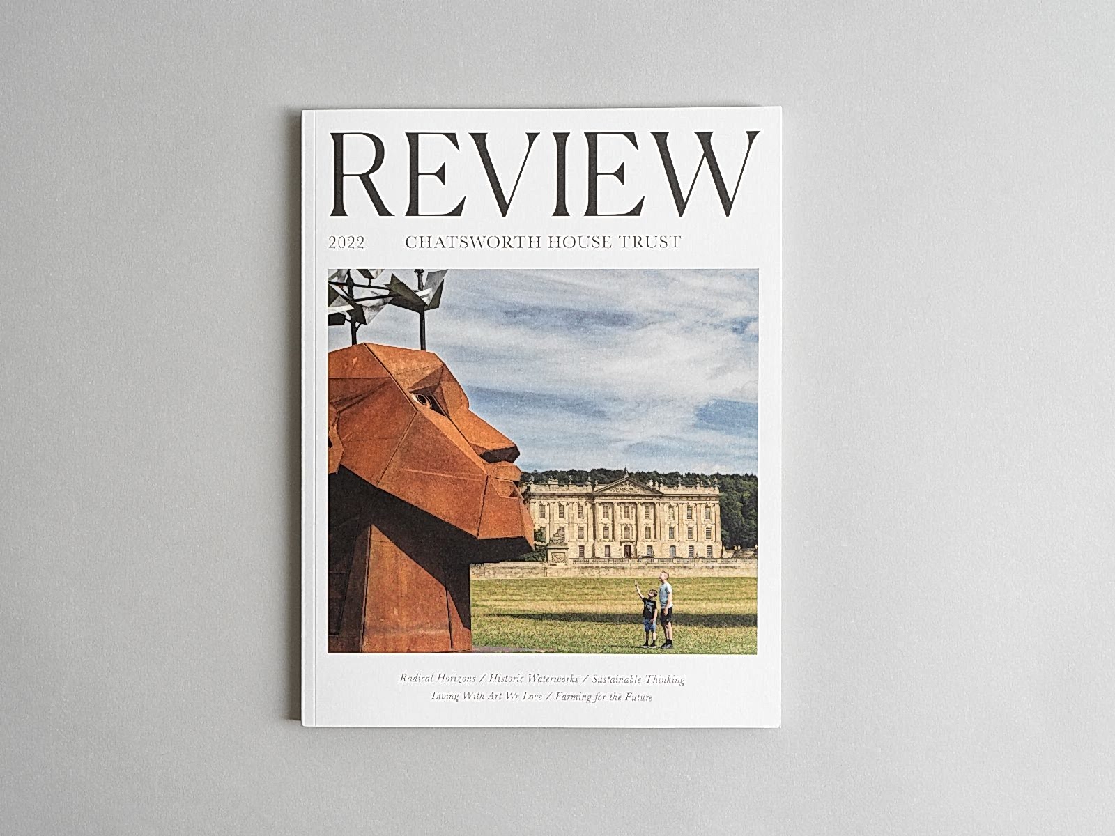 Flat lay of Chatsworth House Trust Annual Review. Front cover featuring a large iron head in front of Chatsworth House. 