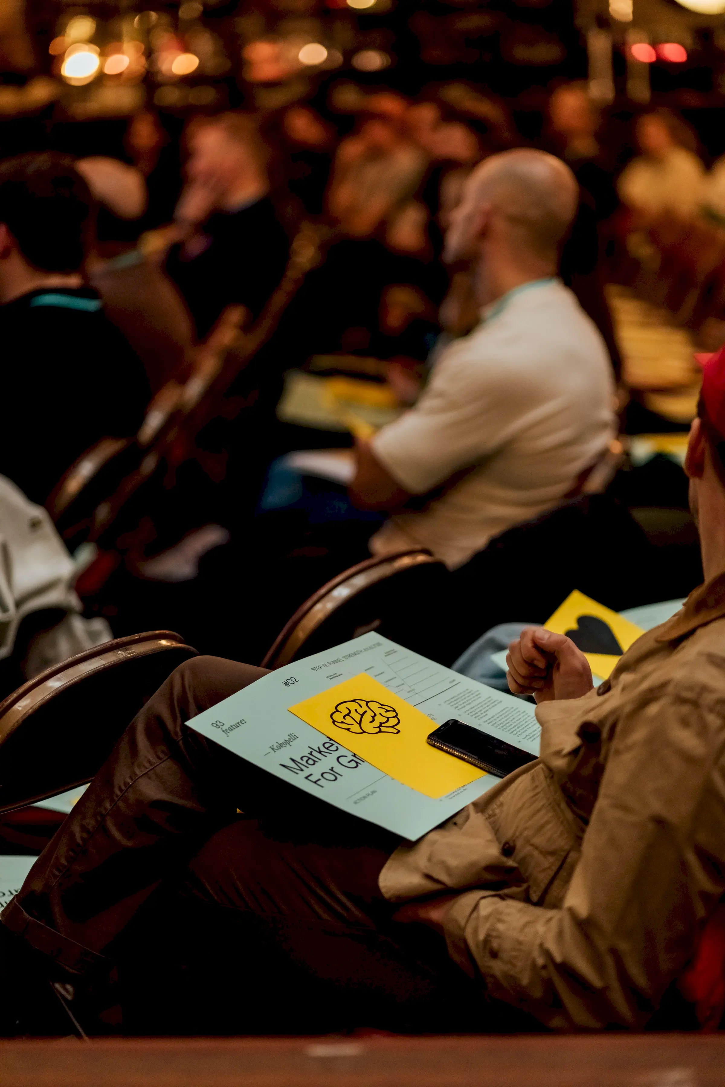 The Marketing for Growth event worksheet and handout on the lap of an attendee, printed on GF Smith Colorplan.