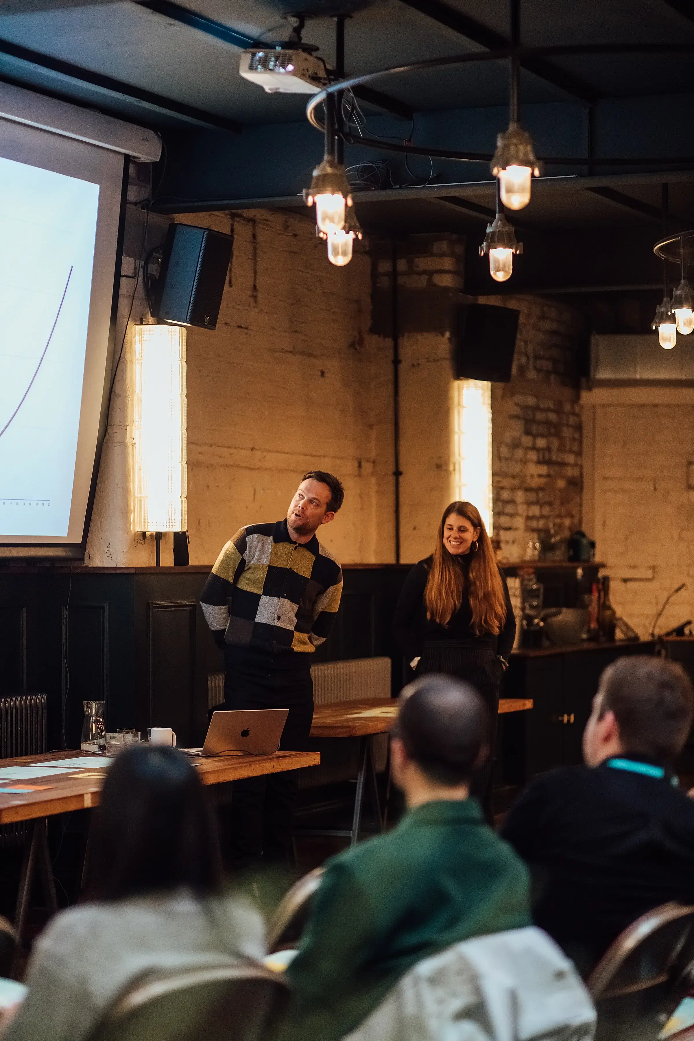 James and Becs of Kokopelli presenting at the event next to the big screen in The Mowbray.