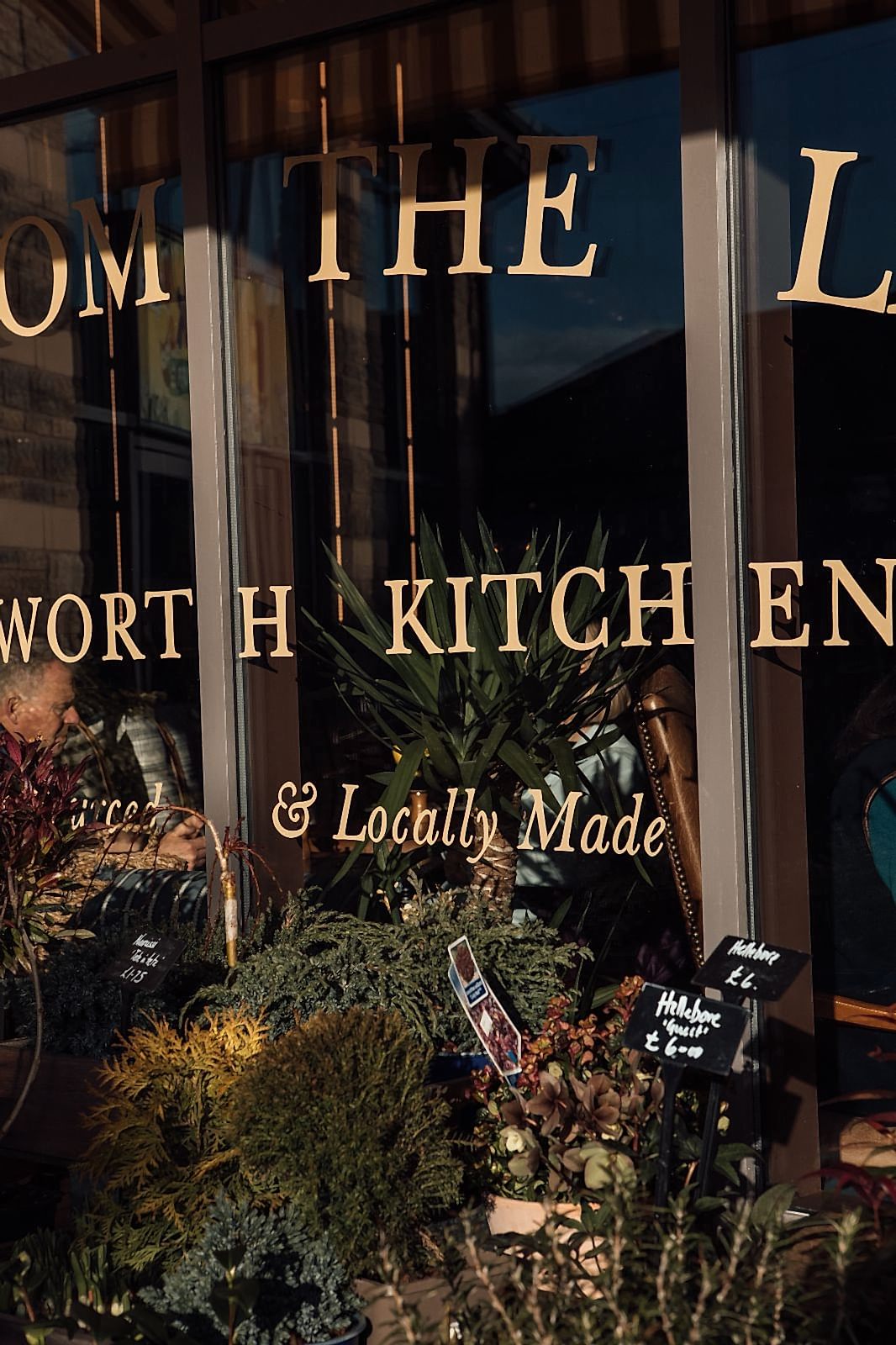 Close up of sign writing on Chatsworth Kitchen window. LOCALLY MADE. Flowers are for sale in the foreground.