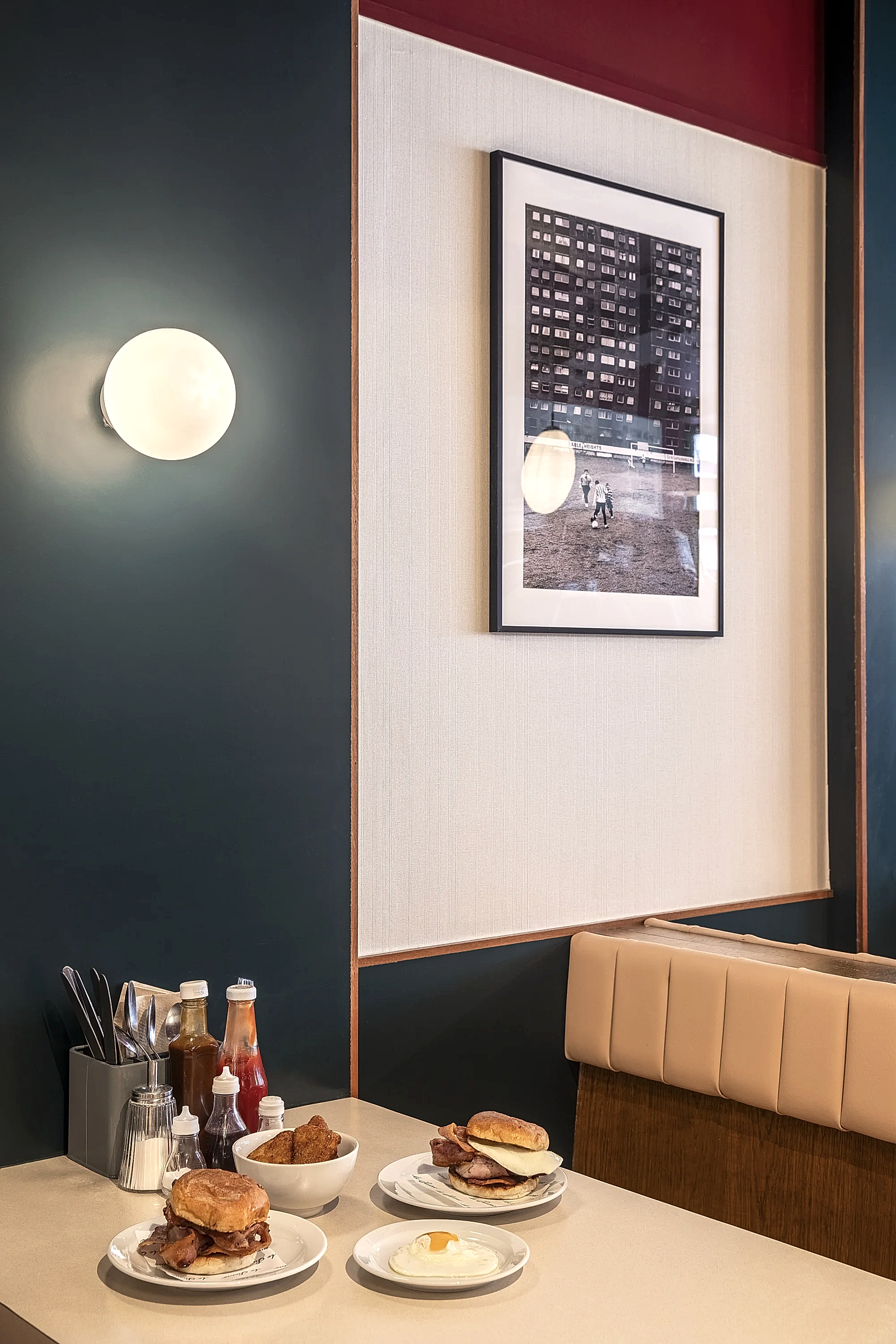 Seating arrangement. Traditional British fry-up cafe food placed on table with sauces and cutlery.