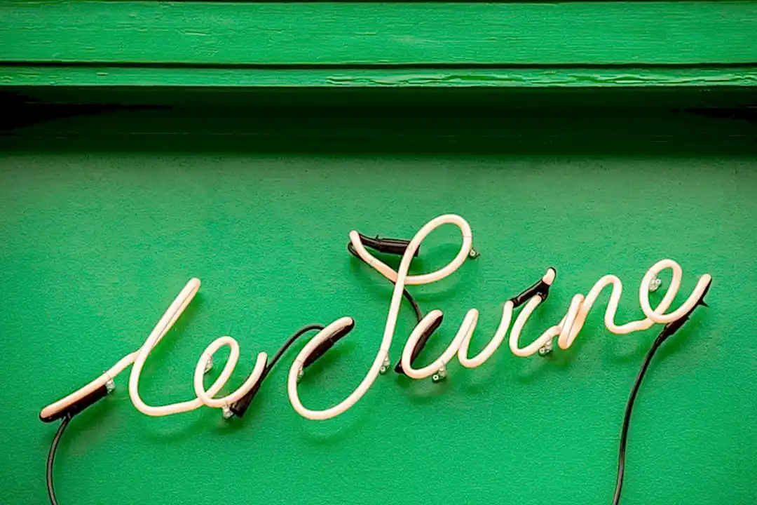 Custom Le Swine neon signage on painted green facade.