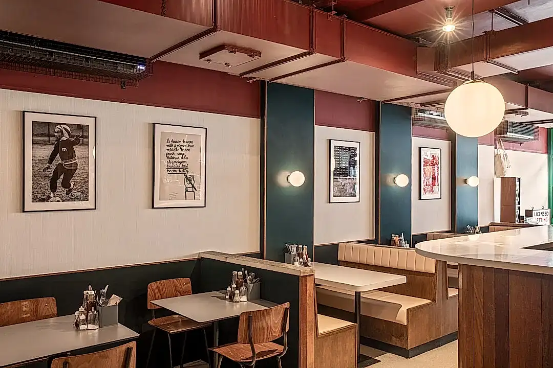 Le Swine interior image. Wood cladding, stone countertop, vinyl banquette seating, circular lighting, deep red and slate grey colours.