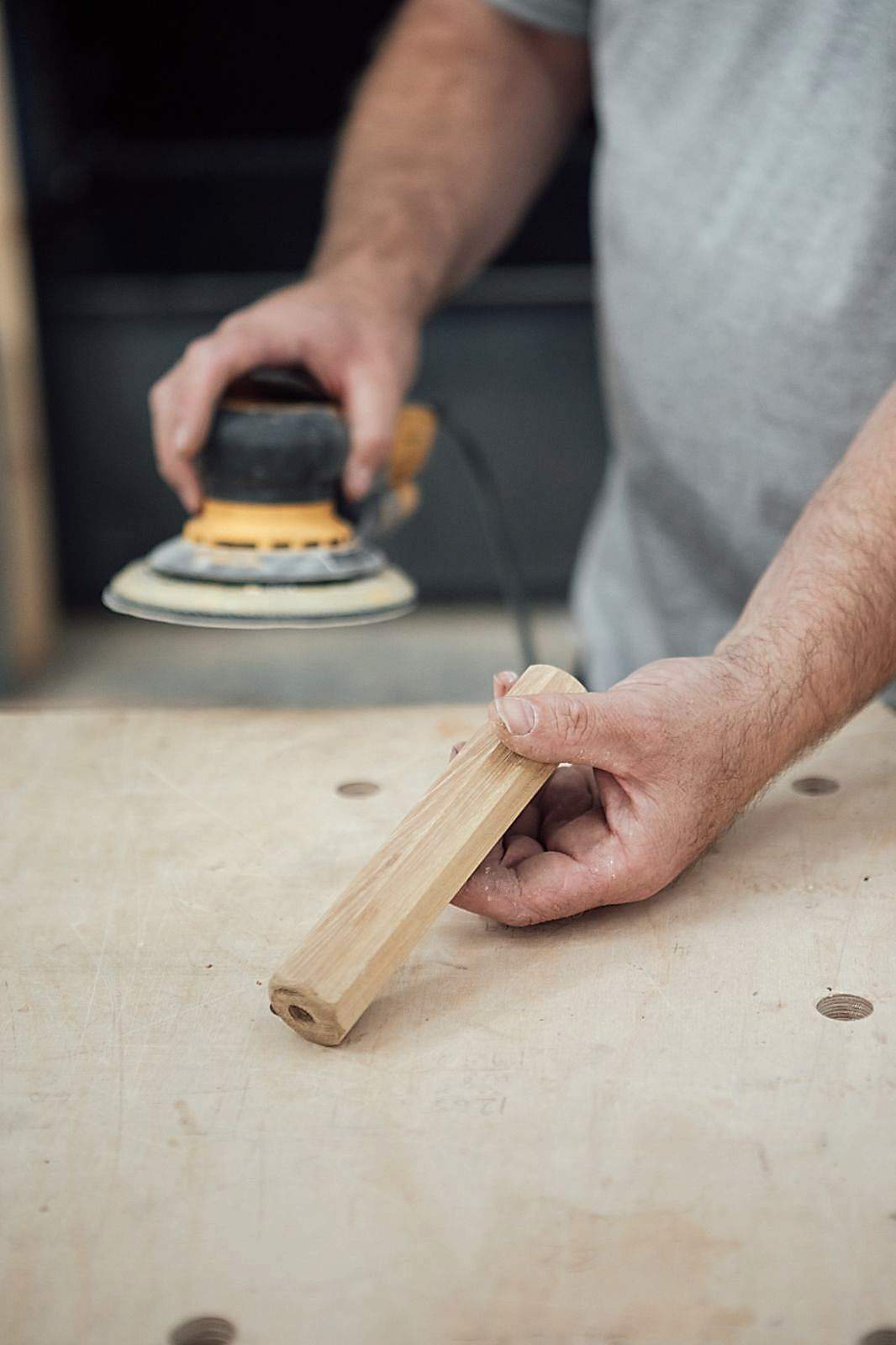 Close up of man holding an electric sander in one hand 