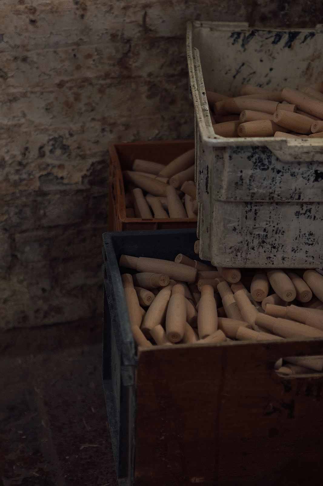 Three plastic boxes filled with pristine, light brown turned wood handles at Woodware Repetitions in Sheffield.