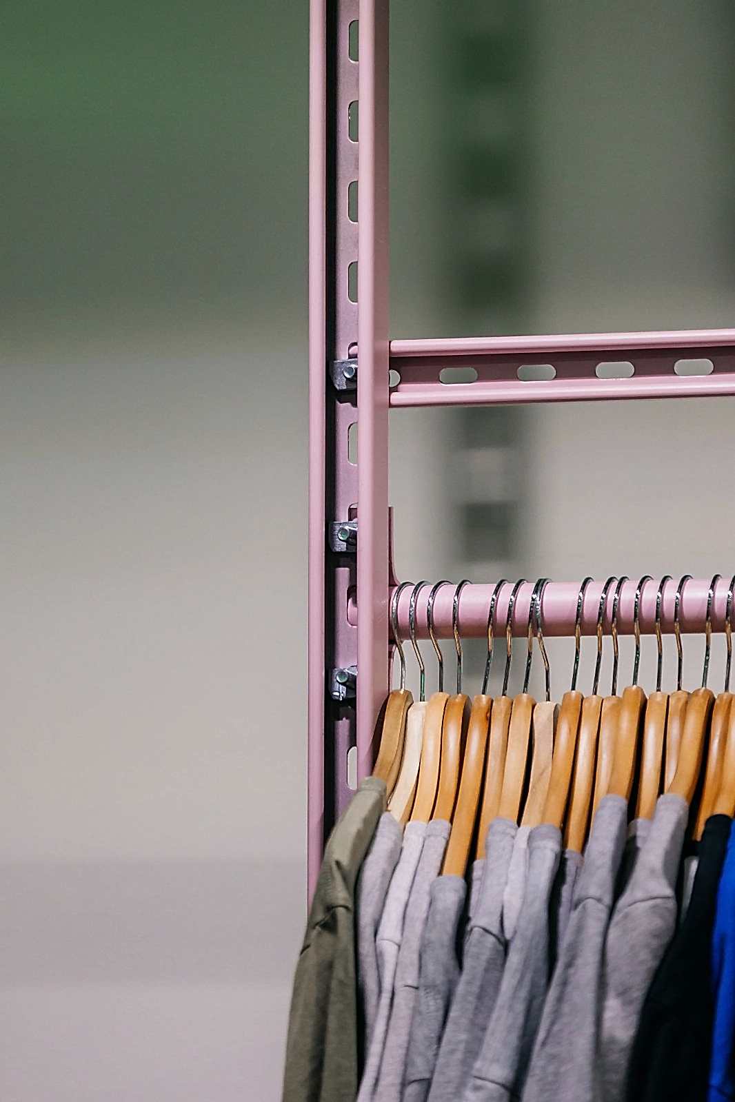 Pink powder-coated unistrut shelving system as railing hanging t-shirts for vintage clothing store in Sheffield