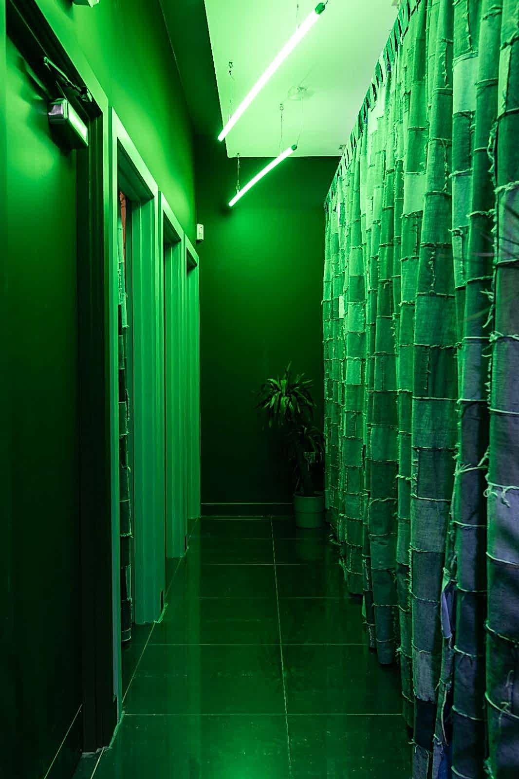 Shop dressing rooms with upcycled patched-denim curtains and two L.E.D tube lights tinting the space green