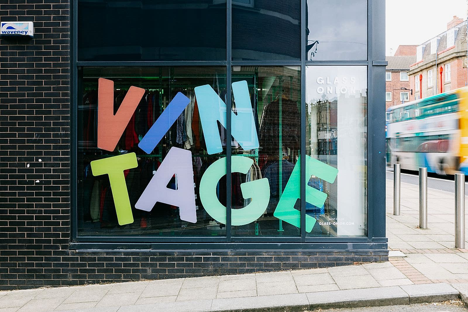 Large side window of Glass Onionâ€™s Sheffield store with big multi-coloured vinyl letters reading Vintage in a stacked design. 