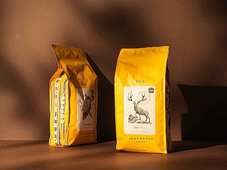 93 branding for Dark woods wholesale coffee. Two yellow bags with an owl and stag motif. Great Taste award sticker on bag. 