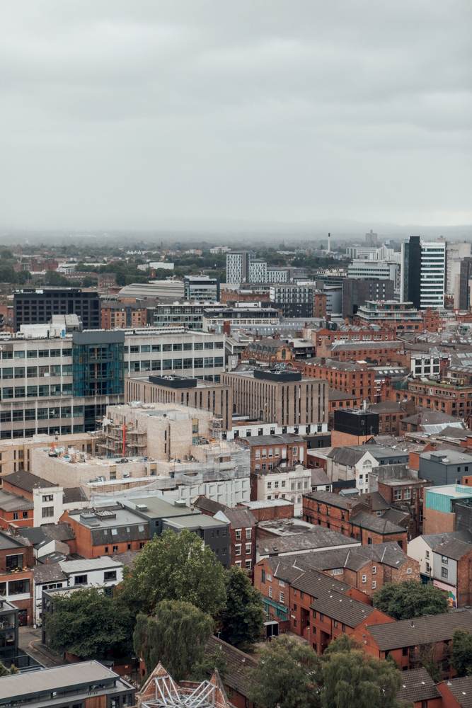 View from Swan Street House over Manchester, red brick buildings and trees. Soft grey daytime lighting.