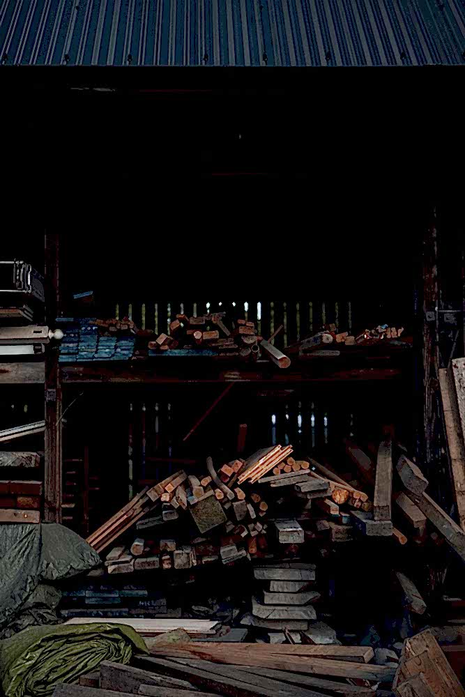 Covered woodstore with shelves and stacks of reclaimed planks and posts of varying colours.