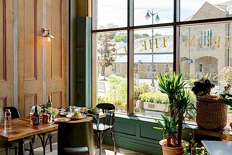 Room with wood panelling, a table laid out with food & plants. A large window has gold letters painted across it in reverse. 