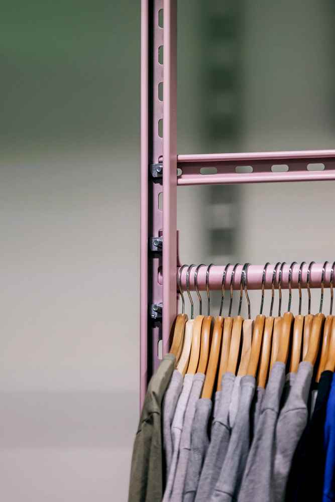 Pink powder-coated unistrut shelving system as railing hanging t-shirts for vintage clothing store in Sheffield