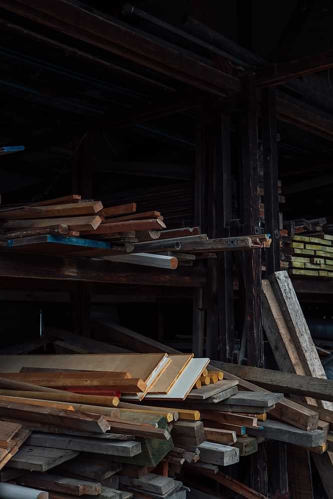 Assortment of reclaimed wooden planks of different sizes and colours stacked in a wood yard on Chatsworth Estate. 